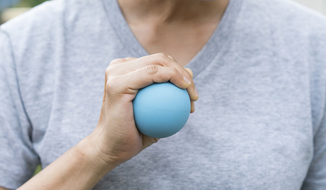 man squeezing blue rubber ball with hand