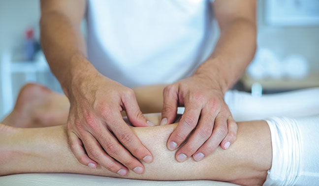 osteopath presses thumbs into leg of woman