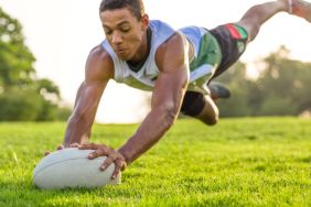 Young athlete falling on rugby ball