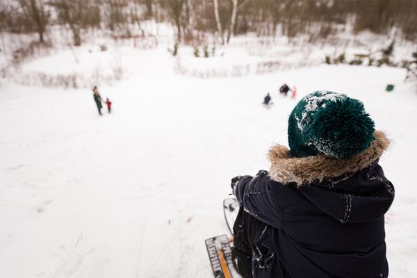 a child outside about to go downhill in a toboggan