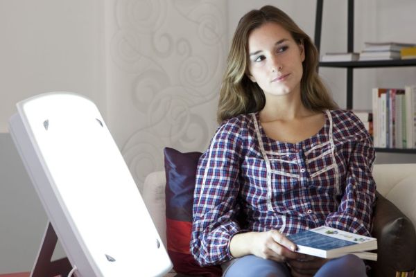 Woman sitting next to light therapy lamp