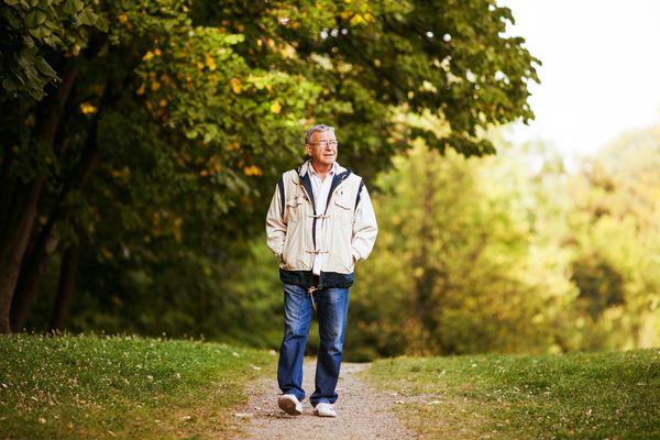 an elderly man walking in a park 