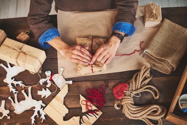 hands wrapping gifts with various symbols of holidays