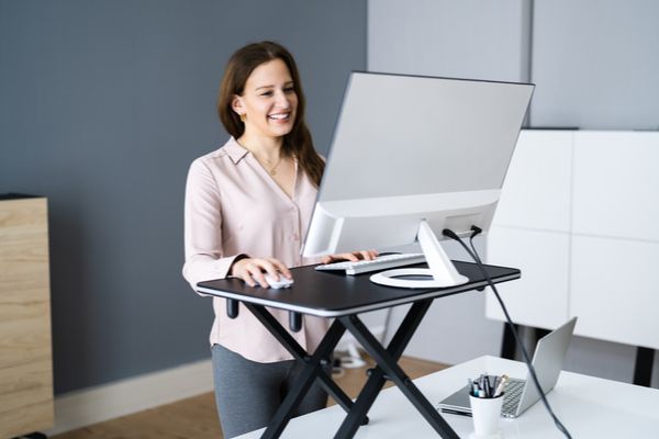 A woman standing in front of a standing desk in her office.