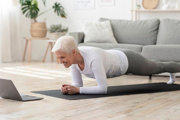 a woman doing a plank exercise indoors facing a computer