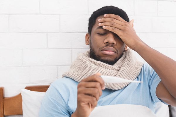 a man checking his temperature in bed 