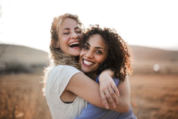 Two female best friends hugging outside 