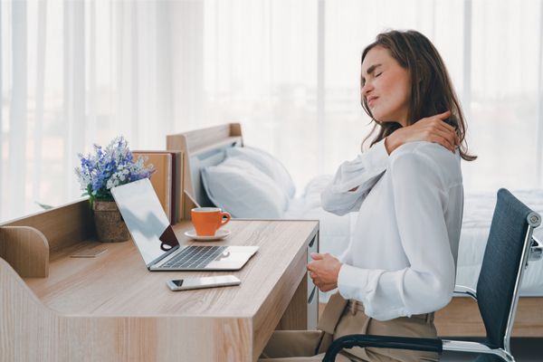 woman sitting at a desk in pain 