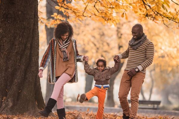 couple with a child moving among fall leaves