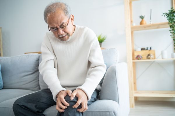 A man holding his knee at home in pain