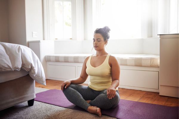 woman practicing meditation in her bedroom