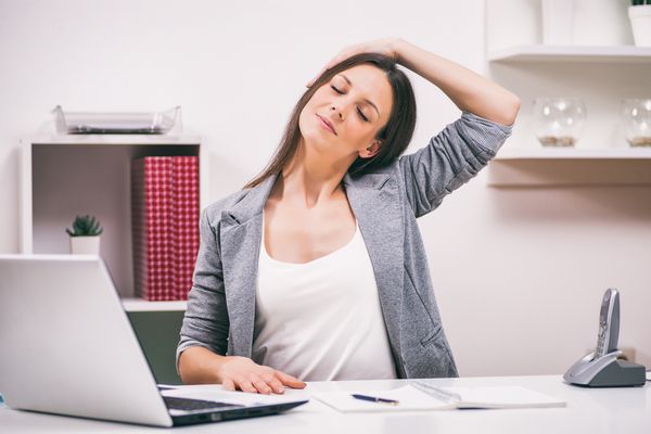 a woman in front of a desk doing neck exercises