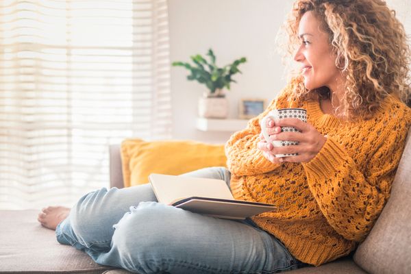 A woman enjoying a cup of coffee and a book 