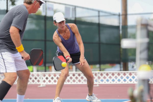 A man and a woman playing pickle ball on a court 