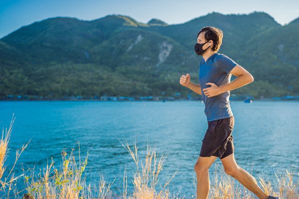 young man running outdoors with a mask on