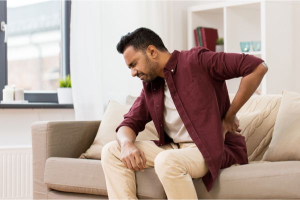 a man sitting on a couch suffering from back pain