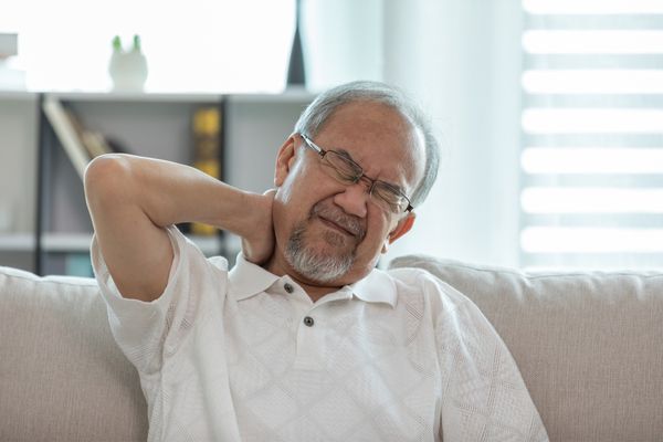 an elderly man experiencing neck pain