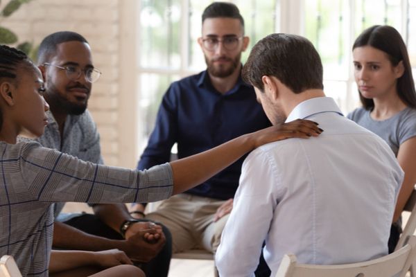 a man being comforted in a group therapy session 