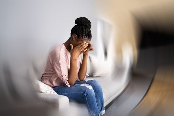 woman experiencing dizziness sitting on a couch at home 