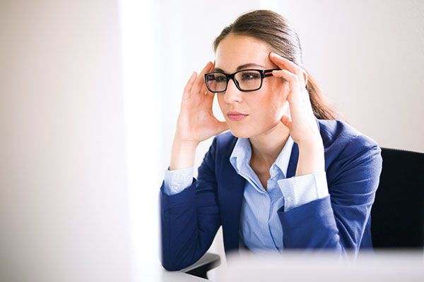 Woman with glasses at the computer and with a headache