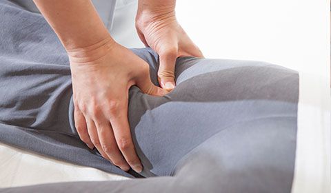 physiotherapist presses thumbs into back of thigh