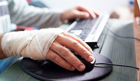 bandaged hand using a mouse at computer