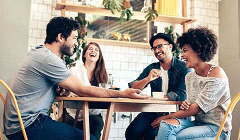 four friends at a cafe laughing