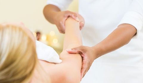 physiotherapist massage upper arm of patient