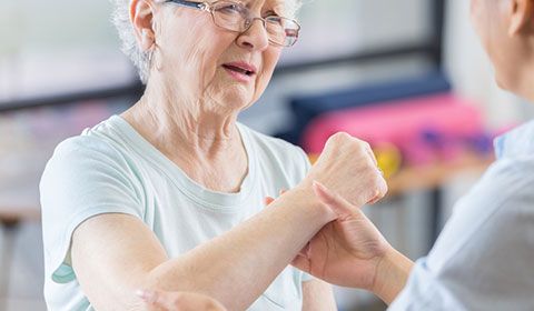 an older woman having her shoulder assessed