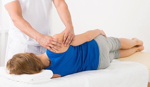 physiotherapist manipulates shoulder of patient