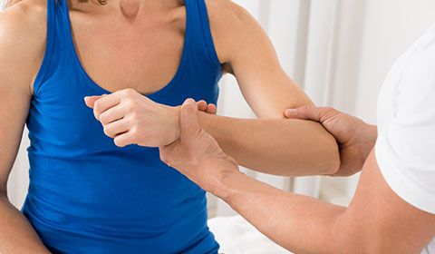 physiotherapist holds patient forearm and elbow