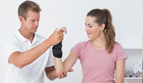 physiotherapist holds arm of patient with wrist brace