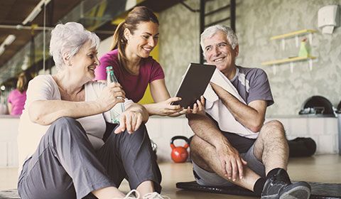 physiotherapist sits with senior couple in the gym