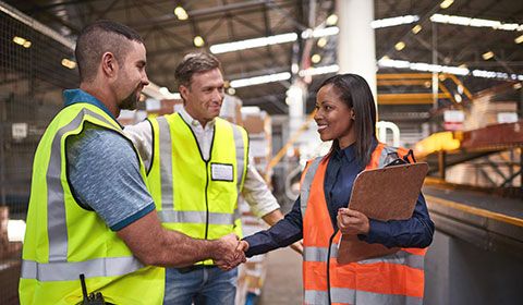 three people in warehouse talking shaking hands