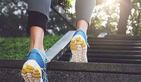 woman wearing athletic shoes walking up steps