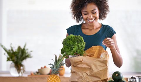 woman kitchen unpacking grocery bag broccoli pineapple