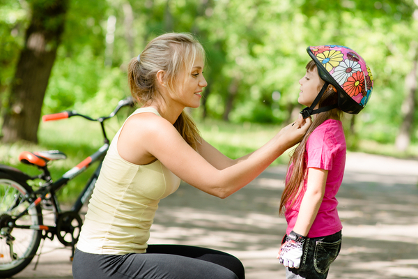 A woman putting a helmet on a kid