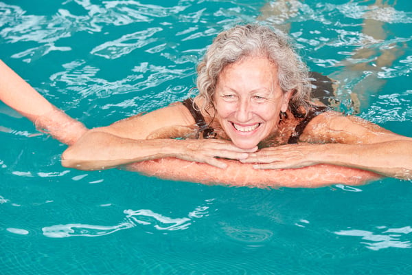 a woman using a pool noodle swimming