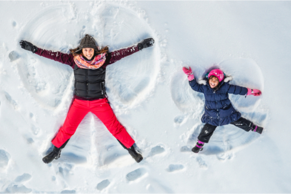 a woman and a kid making snow angels