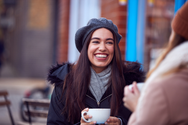 two friends socializing outdoors on a cafe patio 