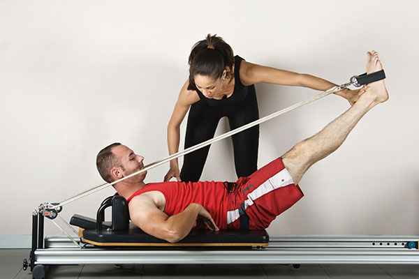 man working with physiotherapist on machine