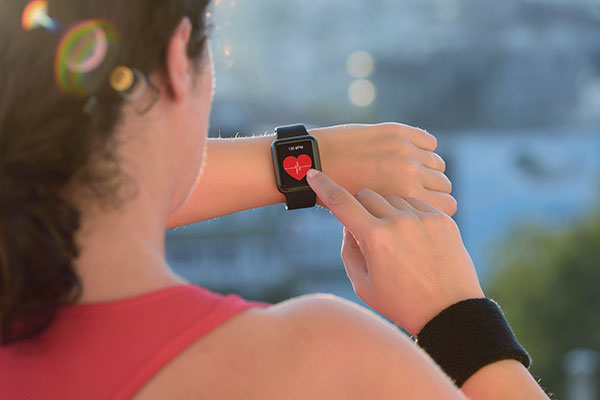 woman checking a heart rate monitor while exercising with cancer