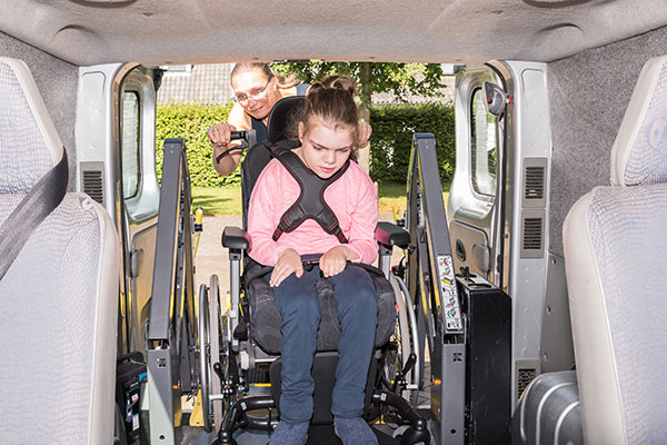 occupational therapist helps girl in wheelchair get into accessible van