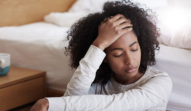 woman sitting on floor with eyes closed and hand on forehead