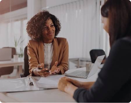 Women speaking across the desk from another