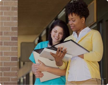 Women standing outside reading through a booklet