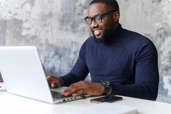 A black man with glasses working on a laptop