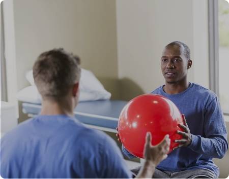 Two men passing back and forth a yoga ball