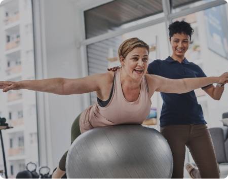 A Women balancing on a yoga ball with a lifemark therapist