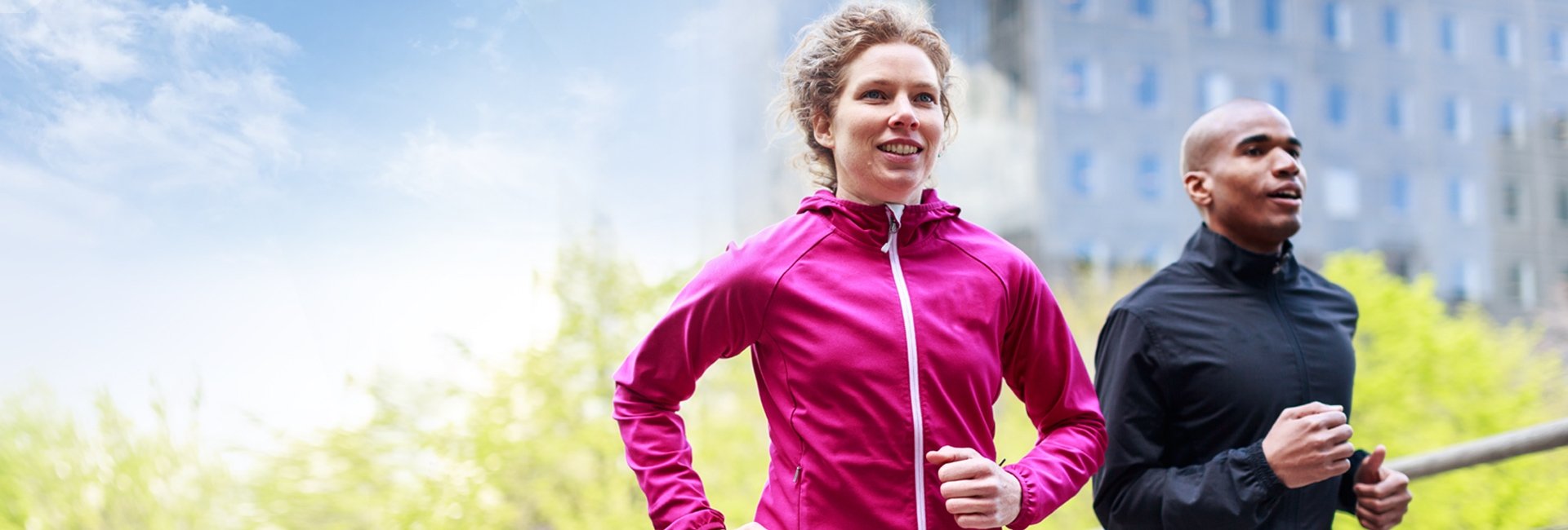 Two people running outside with trees in the background